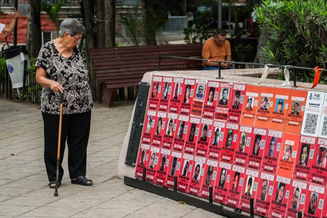 A woman looks closely at a memorial for victims of enforced disappearance located in downtown Culiacan, Sinaloa state, Mexico, on February 9, 2026. Three of the 10 employees of a Canadian mining company who were kidnapped two weeks ago in Mexico's violence-plagued Sinaloa state have been found dead, Mexico's Mining Chamber said on February 9. (Photo by Jesus Verdugo / AFP)