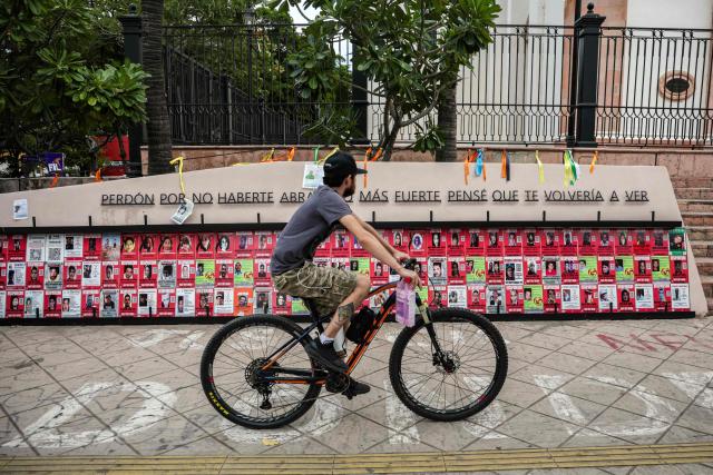 A cyclist rides past a memorial for victims of enforced disappearance located in downtown Culiacan, Sinaloa state, Mexico, on February 9, 2026. Three of the 10 employees of a Canadian mining company who were kidnapped two weeks ago in Mexico's violence-plagued Sinaloa state have been found dead, Mexico's Mining Chamber said on February 9. (Photo by Jesus Verdugo / AFP)