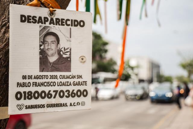 A photo of a missing person hangs from a tree in downtown Culiacan, Sinaloa state, Mexico, on February 9, 2026. Three of the 10 employees of a Canadian mining company who were kidnapped two weeks ago in Mexico's violence-plagued Sinaloa state have been found dead, Mexico's Mining Chamber said on February 9. (Photo by Jesus Verdugo / AFP)
