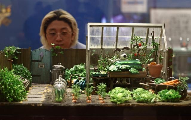 People look at the 'Gromit in the Greenhouse' set from Wallace & Gromit: The Curse of the Were-Rabbit, 2005, during a photocall for the Inside Aardman: Wallace & Gromit and Friends exhibition at the Young V&A museum in London on February 9, 2026, to mark the 50th anniversary of British Oscar-winning animation studio Aardman. (Photo by Henry NICHOLLS / AFP)