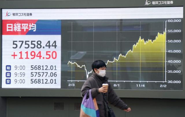 A pedestrian walks past an electronic quotation board displaying numbers of the Nikkei Stock Average on the Tokyo Stock Exchange and a graph showing stock price movements since last year in Tokyo on February 10, 2026. (Photo by Kazuhiro NOGI / AFP)