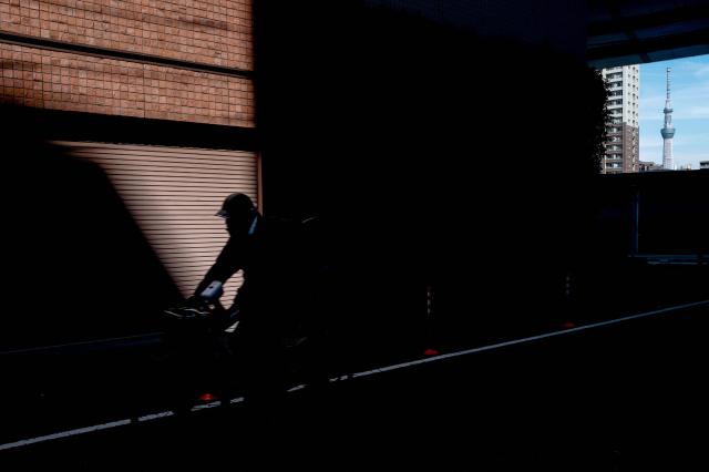 TOPSHOT - A person rides a bicycle as the Tokyo Skytree is seen in the background in Tokyo on February 10, 2026. (Photo by Philip FONG / AFP)