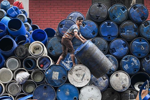 TOPSHOT - A worker stacks empty drums outside a shop at a marketplace ahead of Bangladesh's general election in Dhaka on February 10, 2026. (Photo by Sajjad HUSSAIN / AFP)