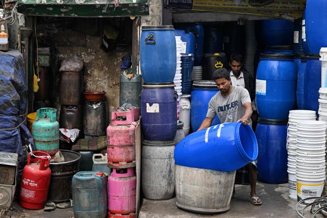 A worker cleans drums outside a shop at a marketplace ahead of Bangladesh's general election in Dhaka on February 10, 2026. (Photo by Sajjad HUSSAIN / AFP)