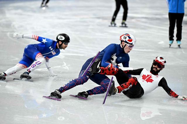 Canada's Steven Dubois and Britain's Niall Treacy crash in front of US' Clayton Declemente during the short track speed skating men's 1000m heats during the Milano Cortina 2026 Winter Olympic Games at Milano Ice Skating Arena in Milan on February 10, 2026. (Photo by Gabriel BOUYS / AFP)