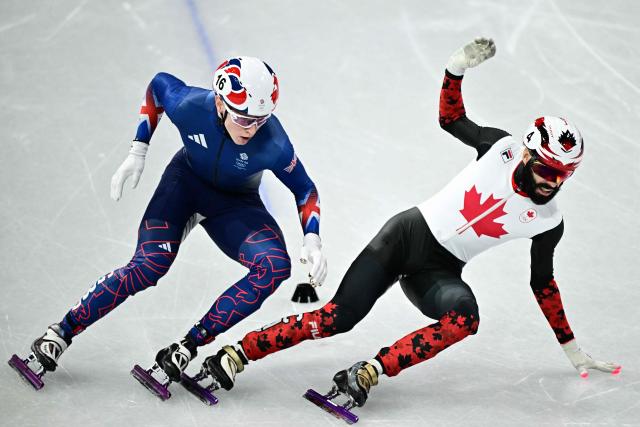 Canada's Steven Dubois and Britain's Niall Treacy compete in the short track speed skating men's 1000m heats during the Milano Cortina 2026 Winter Olympic Games at Milano Ice Skating Arena in Milan on February 10, 2026. (Photo by JULIEN DE ROSA / AFP)