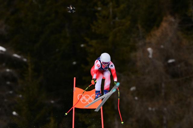 Switzerland's Janine Schmitt competes as a video drone flies overhead during the downhill run of the women's team combined event during the Milano Cortina 2026 Winter Olympic Games at the Tofane Alpine Skiing Centre in Cortina d’Ampezzo on February 10, 2026. (Photo by Stefano RELLANDINI / AFP)