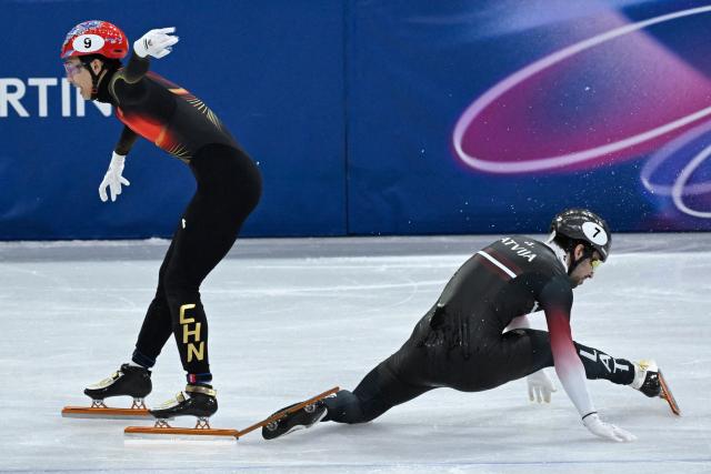 Latvia's Roberts Kruzbergs crashes as China's Sun Long competes in the short track speed skating men's 1000m heats during the Milano Cortina 2026 Winter Olympic Games at Milano Ice Skating Arena in Milan on February 10, 2026. (Photo by WANG Zhao / AFP)