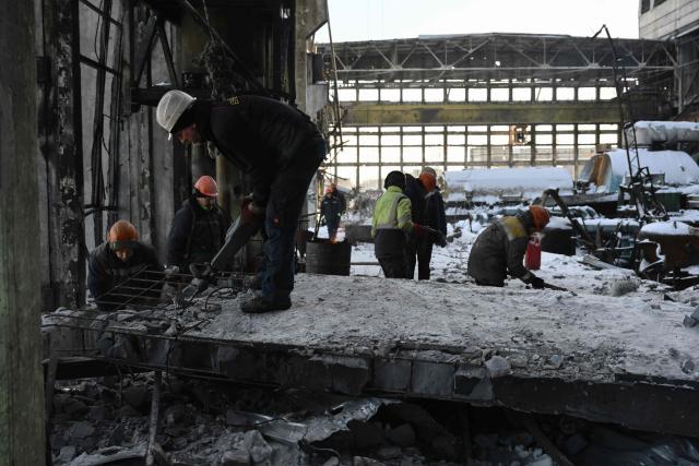 Employees clear debris at a heavily damaged thermal power plant of the Ukrainian energy provider DTEK in an undisclosed location in Ukraine on February 9, 2026, following Russian missile and drone strikes amid the Russian invasion of Ukraine. (Photo by Genya SAVILOV / AFP)