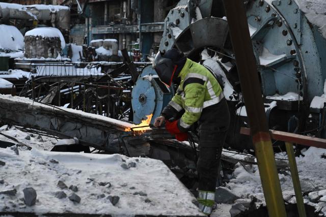 An employee clears debris at a heavily damaged thermal power plant of the Ukrainian energy provider DTEK in an undisclosed location in Ukraine on February 9, 2026, following Russian missile and drone strikes amid the Russian invasion of Ukraine. (Photo by Genya SAVILOV / AFP)