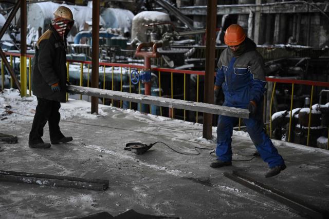 Employees clear debris at a heavily damaged thermal power plant of the Ukrainian energy provider DTEK in an undisclosed location in Ukraine on February 9, 2026, following Russian missile and drone strikes amid the Russian invasion of Ukraine. (Photo by Genya SAVILOV / AFP)