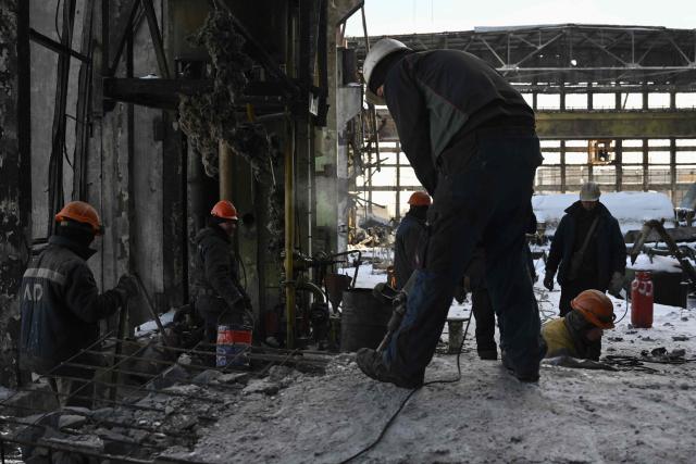 Employees clear debris at a heavily damaged thermal power plant of the Ukrainian energy provider DTEK in an undisclosed location in Ukraine on February 9, 2026, following Russian missile and drone strikes amid the Russian invasion of Ukraine. (Photo by Genya SAVILOV / AFP)