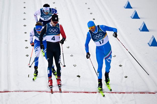 Italy's Simone Mocellini (R) crosses the finish line ahead of Czech Republic's Jiri Tuz in heat 3 of the men's cross country sprint classic quarterfinal event of the Milano Cortina 2026 Winter Olympic Games at Tesero Cross-Country Skiing Stadium in Lago di Tesero (Val di Fiemme), on February 10, 2026. (Photo by Tobias SCHWARZ / AFP)