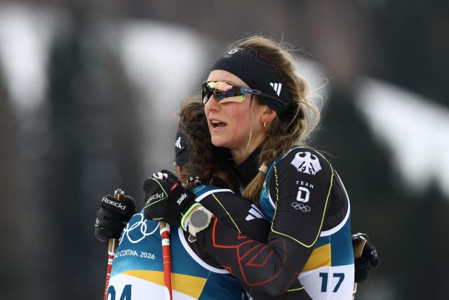 Germany's Laura Gimmler ambraces Germany's Coletta Rydzek after they competed in heat 2 of the women's cross country sprint classic semifinals event of the Milano Cortina 2026 Winter Olympic Games at Tesero Cross-Country Skiing Stadium in Lago di Tesero (Val di Fiemme), on February 10, 2026. (Photo by Anne-Christine POUJOULAT / AFP)