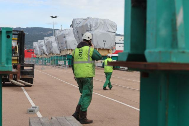 Workers walk towards biofuel engines stored at the Ajaccio's port prior to their installation at the new Ajaccio's Ricanto electric central, in Ajaccio on the French Mediterranean island of Corsica on February 10, 2026. (Photo by Pascal POCHARD-CASABIANCA / AFP)