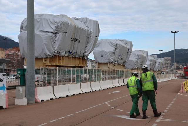 Workers walk by biofuel engines stored at the Ajaccio's port prior to their installation at the new Ajaccio's Ricanto electric central, in Ajaccio on the French Mediterranean island of Corsica on February 10, 2026. (Photo by Pascal POCHARD-CASABIANCA / AFP)