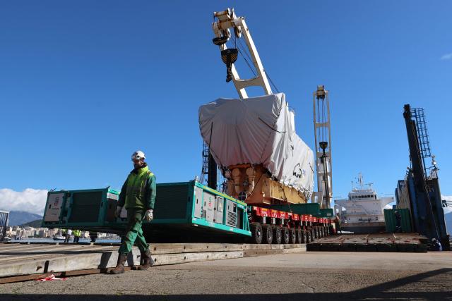 Workers unload a biofuel engine from a bunkering vessel at the Ajaccio's port prior to their installation at the new Ajaccio's Ricanto electric central, in Ajaccio on the French Mediterranean island of Corsica on February 10, 2026. (Photo by Pascal POCHARD-CASABIANCA / AFP)