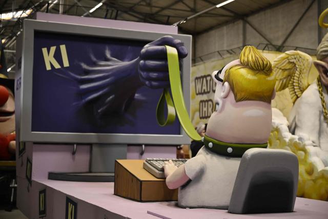 A carnival float depicts an arm coming from an computer screen and holding the user at a leash during a presentation of this year's carnival floats of Cologne's carnival committee, on February 10, 2026 in Cologne. (Photo by INA FASSBENDER / AFP)