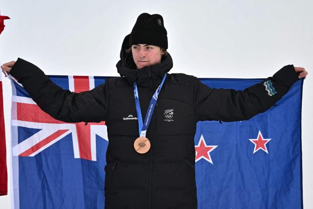 Bronze medallist New Zealand's Luca Harrington celebrates on the podium after the freestyle skiing men's freeski slopestyle final during the Milano Cortina 2026 Winter Olympic Games at Livigno Snow Park, in Livigno (Valtellina), on February 10, 2026. (Photo by Jeff PACHOUD / AFP)