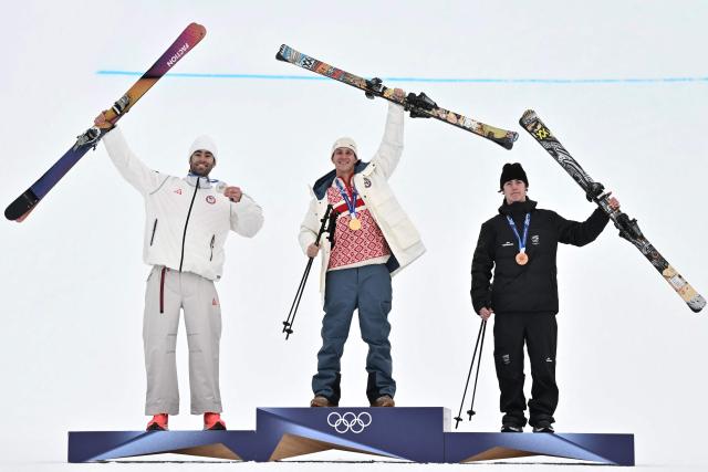 (From L) Silver medallist USA's Alex Hall, gold medallist Norway's Birk Ruud and bronze medallist New Zealand's Luca Harrington celebrate on the podium after the freestyle skiing men's freeski slopestyle final during the Milano Cortina 2026 Winter Olympic Games at Livigno Snow Park, in Livigno (Valtellina), on February 10, 2026. (Photo by Jeff PACHOUD / AFP)