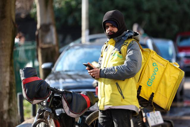 A foreign delivery worker stands next to his bicycle in downtown Zagreb on February 3, 2026. As Croatia struggles with growing staff shortages, particularly in its key tourism sector, experts warn that it is leaving its badly needed foreign workers vulnerable to violence and exploitation. (Photo by MARKO PERKOV / AFP)