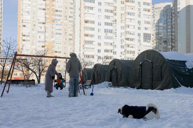 Local residents stand next to emergency service tents set up for those whose homes are without electricity or heating following Russian missile and drone attacks on Ukrainian energy infrastructure, in a residential neighborhood of Kyiv on February 10, 2026, amid the Russian invasion of Ukraine. (Photo by Tetiana DZHAFAROVA / AFP)
