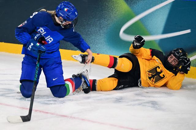 The laces of Italy's #08 Anna Caumo (L) and Germany's #05 Charlott Schaffrath are tangled up during the women's preliminary round Group B Ice Hockey match between Italy and Germany at the Milano Rho Ice Hockey Arena at the Milano Cortina 2026 Winter Olympic Games in Milan, on February 10, 2026. (Photo by Piero CRUCIATTI / AFP)