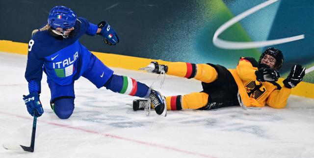 The laces of Italy's #08 Anna Caumo (L) and Germany's #05 Charlott Schaffrath are tangled up during the women's preliminary round Group B Ice Hockey match between Italy and Germany at the Milano Rho Ice Hockey Arena at the Milano Cortina 2026 Winter Olympic Games in Milan, on February 10, 2026. (Photo by Piero CRUCIATTI / AFP)