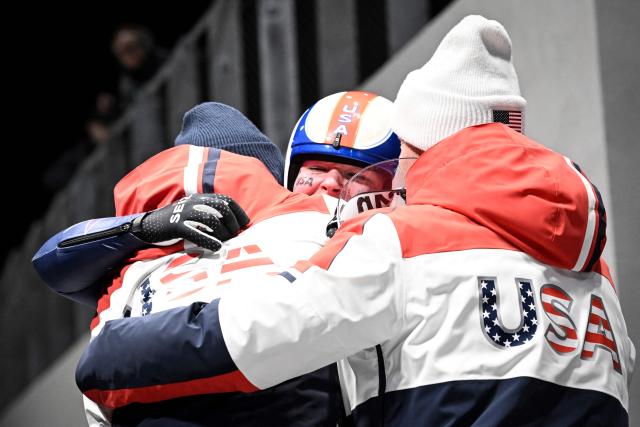 USA's Ashley Farquharson celebrates with her team as she crosses the finish line in the luge women's singles run 4 at Cortina Sliding Centre during the Milano Cortina 2026 Winter Olympic Games in Cortina d'Ampezzo on February 10, 2026. (Photo by Tiziana FABI / AFP)