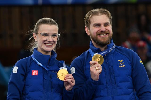 Sweden's gold medalists Isabella Wranaa and Rasmus Wrana hold up their medals on the podium of the curling mixed doubles event during the Milano Cortina 2026 Winter Olympic Games at the Cortina Curling Olympic Stadium in Cortina d’Ampezzo on February 10, 2026. (Photo by Franзois-Xavier MARIT / AFP)