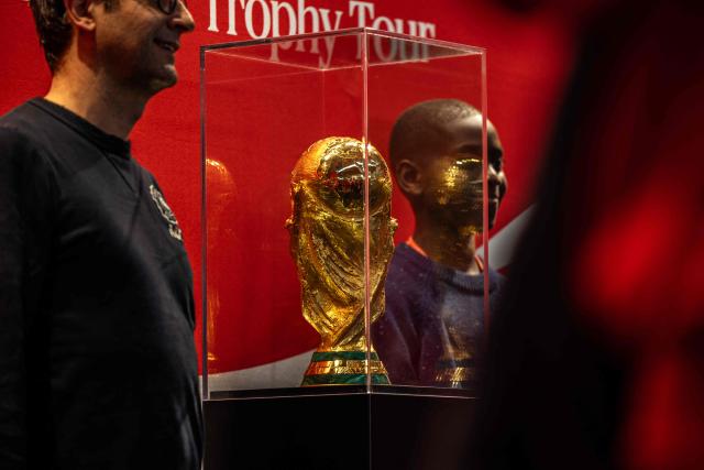 Visitors pose by the 2026 FIFA World Cup trophy displayed during a public event at the Adidas store in Paris on February 10, 2026. (Photo by Guillaume BAPTISTE / AFP)