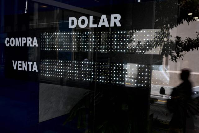 A sign with the price of the US dollar is seen on thw window of a bank in Buenos Aires, on February 10, 2026. Inflation remained practically stable in January in Argentina, closing at 2.9%, the Indec statistics institute announced on Tuesday. Its director resigned last week after opposing the government’s decision to postpone the implementation of a new measurement method. (Photo by Luis ROBAYO / AFP)