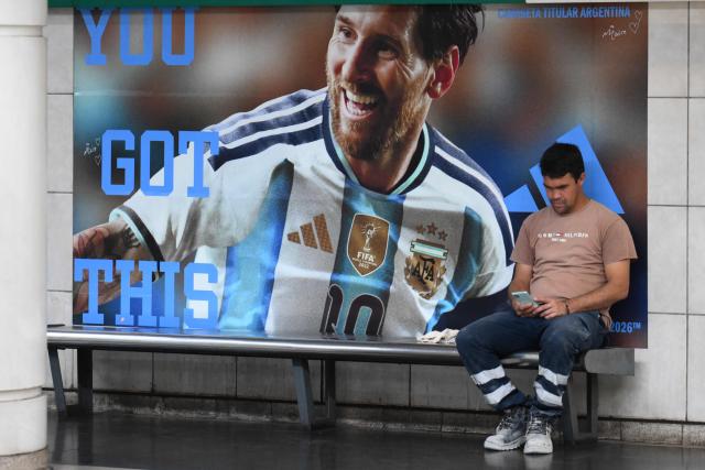 A worker waits for the subway next to a banner with the image of Argentine football star Lionel Messi in Buenos Aires, on February 10, 2026. Inflation remained practically stable in January in Argentina, closing at 2.9%, the Indec statistics institute announced on Tuesday. Its director resigned last week after opposing the government’s decision to postpone the implementation of a new measurement method. (Photo by Luis ROBAYO / AFP)