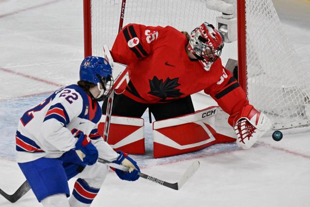 Canada's goalkeeper #35 Ann-Renee Desbiens (R) dives for the puck  during the women's preliminary round Group A Ice Hockey match between Canada and USA at the Milano Santagiulia Ice Hockey Arena during the Milano Cortina 2026 Winter Olympic Games in Milan, on February 10, 2026. (Photo by Alexander NEMENOV / AFP)