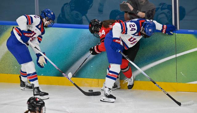 Canada's forward #94 Jennifer Gardiner  (C) vies for the puck with USA's defender #02 Lee Stecklein (L) and USA's forward #24 Joy Dunne (R)  during the women's preliminary round Group A Ice Hockey match between Canada and USA at the Milano Santagiulia Ice Hockey Arena during the Milano Cortina 2026 Winter Olympic Games in Milan, on February 10, 2026. (Photo by Alexander NEMENOV / AFP)