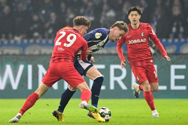 Freiburg's German defender #29 Philipp Treu (L) and Hertha Berlin's German midfielder #22 Marten Winkler (C) vie for the ball during the German Cup (DFB-Pokal) quarter-final football match between Hertha Berlin and SC Freiburg in Berlin on February 10, 2026. (Photo by John MACDOUGALL / AFP) / DFB REGULATIONS PROHIBIT ANY USE OF PHOTOGRAPHS AS IMAGE SEQUENCES AND QUASI-VIDEO.