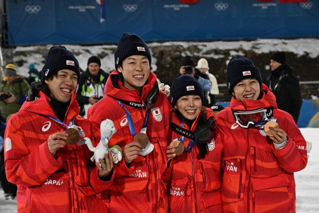 (From L) Bronze medallists Japan's Ren Nikaido, Japan's Ryoyu Kobayashi, Japan's Sara Takanashi and Japan's Nozomi Maruyama celebrate on the podium for the ski jumping mixed team final of the Milano Cortina 2026 Winter Olympic Games at Predazzo Ski Jumping Stadium in Predazzo (Val di Fiemme), on February 10, 2026. (Photo by Javier SORIANO / AFP)