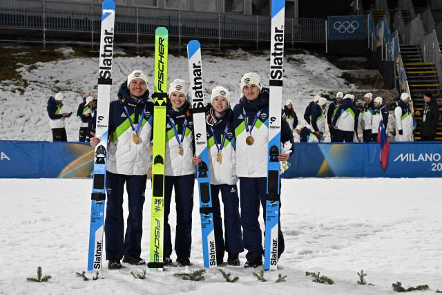 Gold medallists Slovenia's Anze Lanisek (L), Slovenia's Nika Vodan, Slovenia's Nika Prevc and Slovenia's Domen Prevc celebrate winning the ski jumping mixed team final of the Milano Cortina 2026 Winter Olympic Games at Predazzo Ski Jumping Stadium in Predazzo (Val di Fiemme), on February 10, 2026. (Photo by Javier SORIANO / AFP)