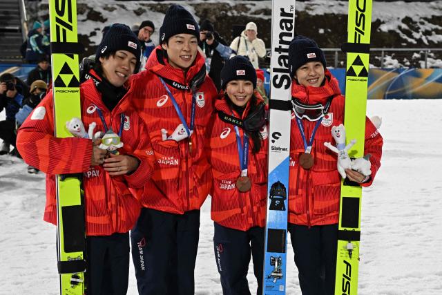 (From L) Bronze medallists Japan's Ren Nikaido, Japan's Ryoyu Kobayashi, Japan's Sara Takanashi and Japan's Nozomi Maruyama celebrate on the podium for the ski jumping mixed team final of the Milano Cortina 2026 Winter Olympic Games at Predazzo Ski Jumping Stadium in Predazzo (Val di Fiemme), on February 10, 2026. (Photo by Javier SORIANO / AFP)