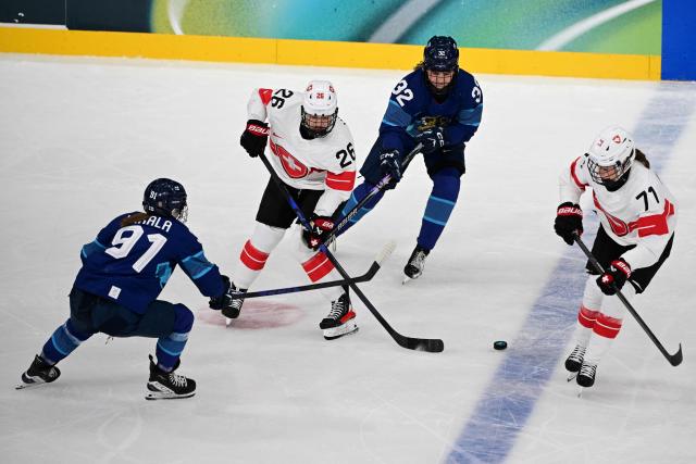 Switzerland's #26 Naemi Herzig (2L) and Switzerland's #71 Lena Marie Lutz (R) vie for the puck with Finland's #91 Julia Liikala (L) and Finland's #32 Emilia Vesa during the women's preliminary round Group A Ice Hockey match between Finland and Switzerland at the Milano Rho Ice Hockey Arena during the Milano Cortina 2026 Winter Olympic Games in Milan, on February 10, 2026. (Photo by Piero CRUCIATTI / AFP)