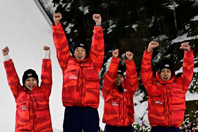 (From L) Bronze medallists Japan's Nozomi Maruyama, Japan's Ryoyu Kobayashi, Japan's Sara Takanashi and Japan's Ren Nikaido celebrate on the podium for the ski jumping mixed team final of the Milano Cortina 2026 Winter Olympic Games at Predazzo Ski Jumping Stadium in Predazzo (Val di Fiemme), on February 10, 2026. (Photo by Tobias SCHWARZ / AFP)