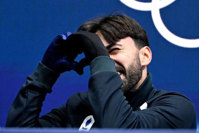 France's Kevin Aymoz reacts at the kiss and cry area after competing in the figure skating men's singles short program during the Milano Cortina 2026 Winter Olympic Games at Milano Ice Skating Arena in Milan on February 10, 2026. (Photo by WANG Zhao / AFP)