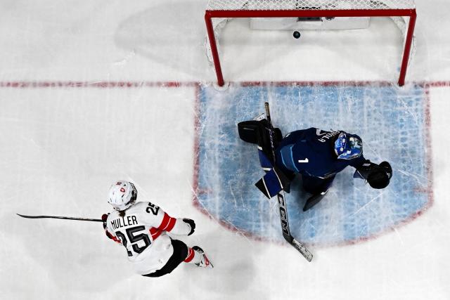 Switzerland's #25 Alina Muller (L) scores the team's first goal against Finland's #01 Sanni Ahola during the women's preliminary round Group A Ice Hockey match between Finland and Switzerland at the Milano Rho Ice Hockey Arena during the Milano Cortina 2026 Winter Olympic Games in Milan, on February 10, 2026. (Photo by Piero CRUCIATTI / AFP)