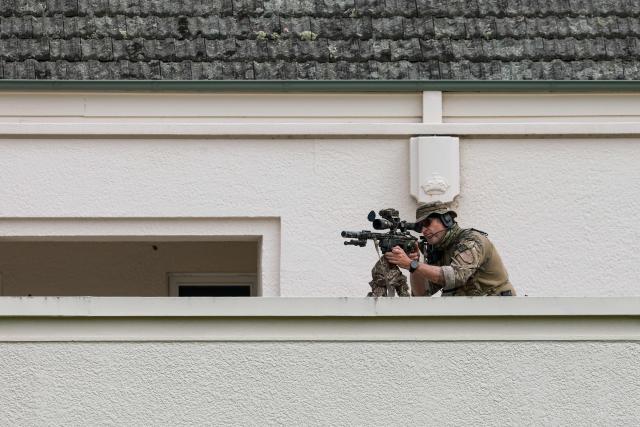 A police sniper is seen on a roof as he secures the area ahead of a welcome ceremony for Israel's President Isaac Herzog at the Government House in Canberra on February 11, 2026. Herzog's tightly secured, four-day trip aims to console Australia's Jewish community after the December shooting at Sydney's Bondi Beach that killed 15 people at a Hanukkah festival. (Photo by DAVID GRAY / AFP)