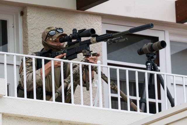 A police sniper is seen on a roof as he secures the area ahead of a welcome ceremony for Israel's President Isaac Herzog at the Government House in Canberra on February 11, 2026. Herzog's tightly secured, four-day trip aims to console Australia's Jewish community after the December shooting at Sydney's Bondi Beach that killed 15 people at a Hanukkah festival. (Photo by DAVID GRAY / AFP)