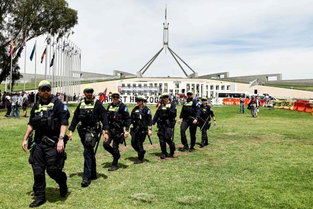 Police officers patrol as protesters gather outside Parliament House ahead of the meeting between Australia's Prime Minister Anthony Albanese and Israel's President Isaac Herzog in Canberra on February 11, 2026. Herzog's tightly secured, four-day trip aims to console Australia's Jewish community after the December shooting at Sydney's Bondi Beach that killed 15 people at a Hanukkah festival. (Photo by David GRAY / AFP)