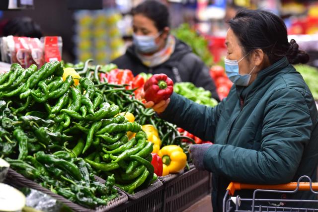 A woman shops for vegetables at a store in Fuyang, in China’s eastern Anhui province on February 11, 2026. Growth in China's consumer prices slowed last month and missed forecasts, official data showed on February 11, as leaders struggle to kickstart domestic spending in the world's second-largest economy. (Photo by CN-STR / AFP) / China OUT