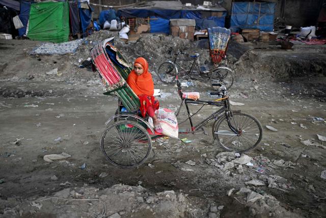 TOPSHOT - A girl waits on a rickshaw near a marketplace in Dhaka on February 11, 2026 ahead of Bangladesh's general elections. (Photo by Sajjad HUSSAIN / AFP)