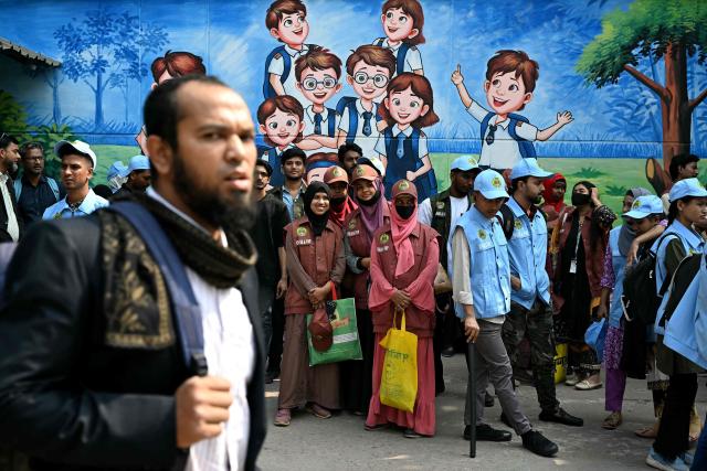 Election commission volunteers wait outside a polling station in Dhaka on February 11, 2026 ahead of Bangladesh's general elections. (Photo by MOHD RASFAN / AFP)