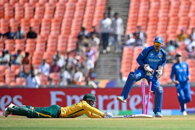 South Africa's Quinton de Kock (L) stretches to reach the crease as Afghanistan's wicketkeeper Rahmanullah Gurbaz reacts during the 2026 ICC Men's T20 Cricket World Cup group stage match between Afghanistan and South Africa at the Narendra Modi Stadium in Ahmedabad on February 11, 2026. (Photo by Shammi MEHRA / AFP)